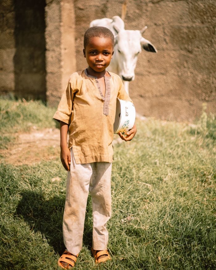 Mastering the First Impression: Your intriguing post title goes here Young child holding a bowl outdoors in Kaduna, Nigeria, showcasing local life.